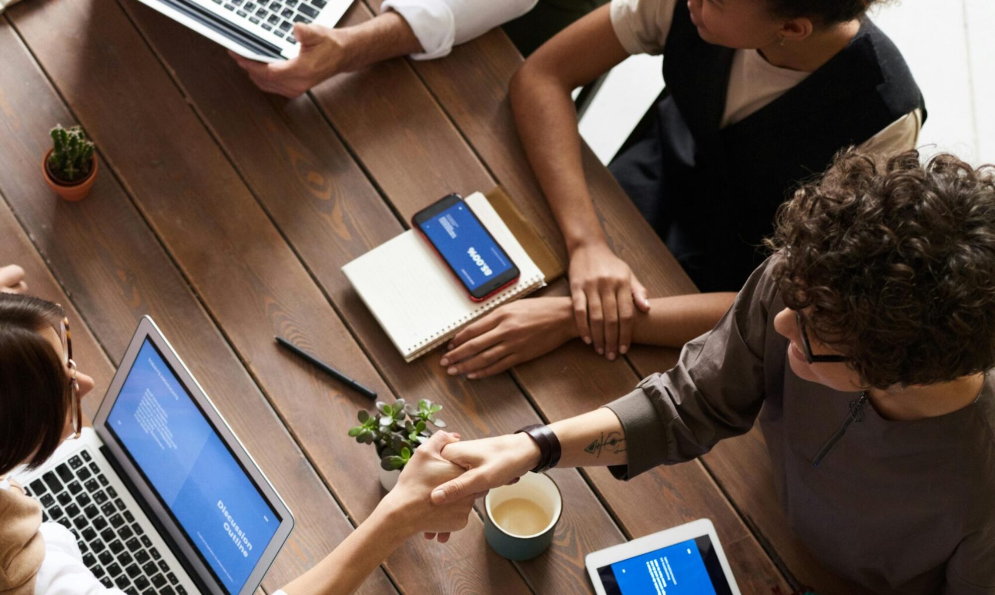 A diverse group of professionals brainstorming in a modern workspace with laptops and notebooks.